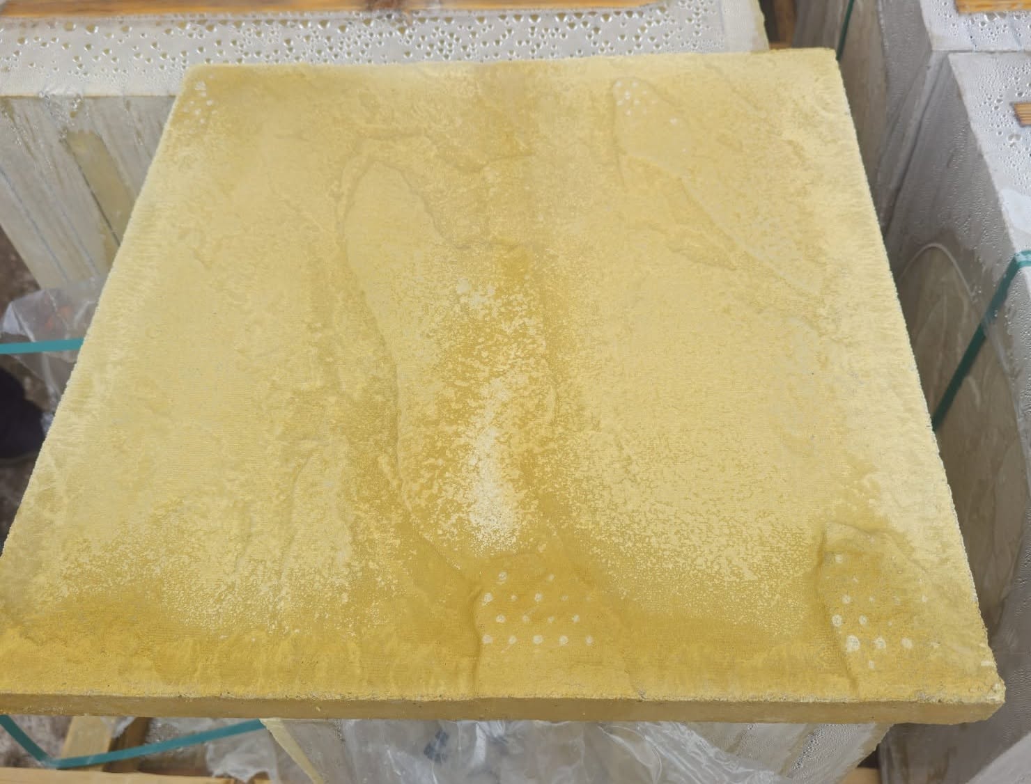 Close-up of a buff sandstone paving slab with its natural riven texture, on a stack of stock