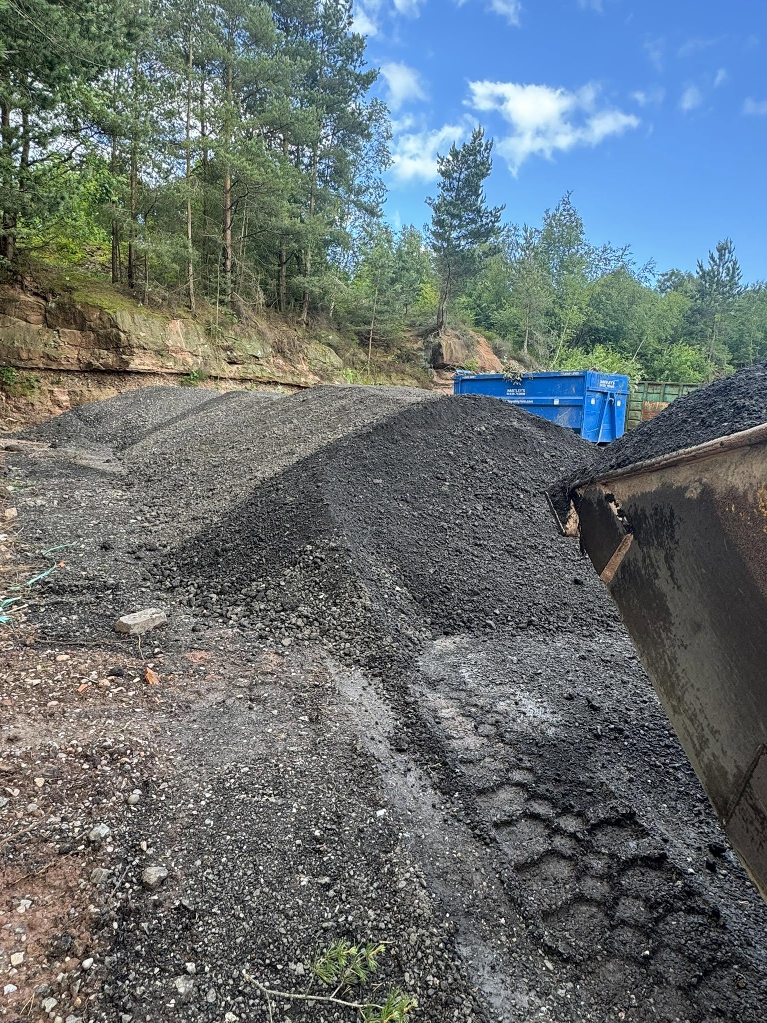 A large stockpile of processed road planings against the old quarry face