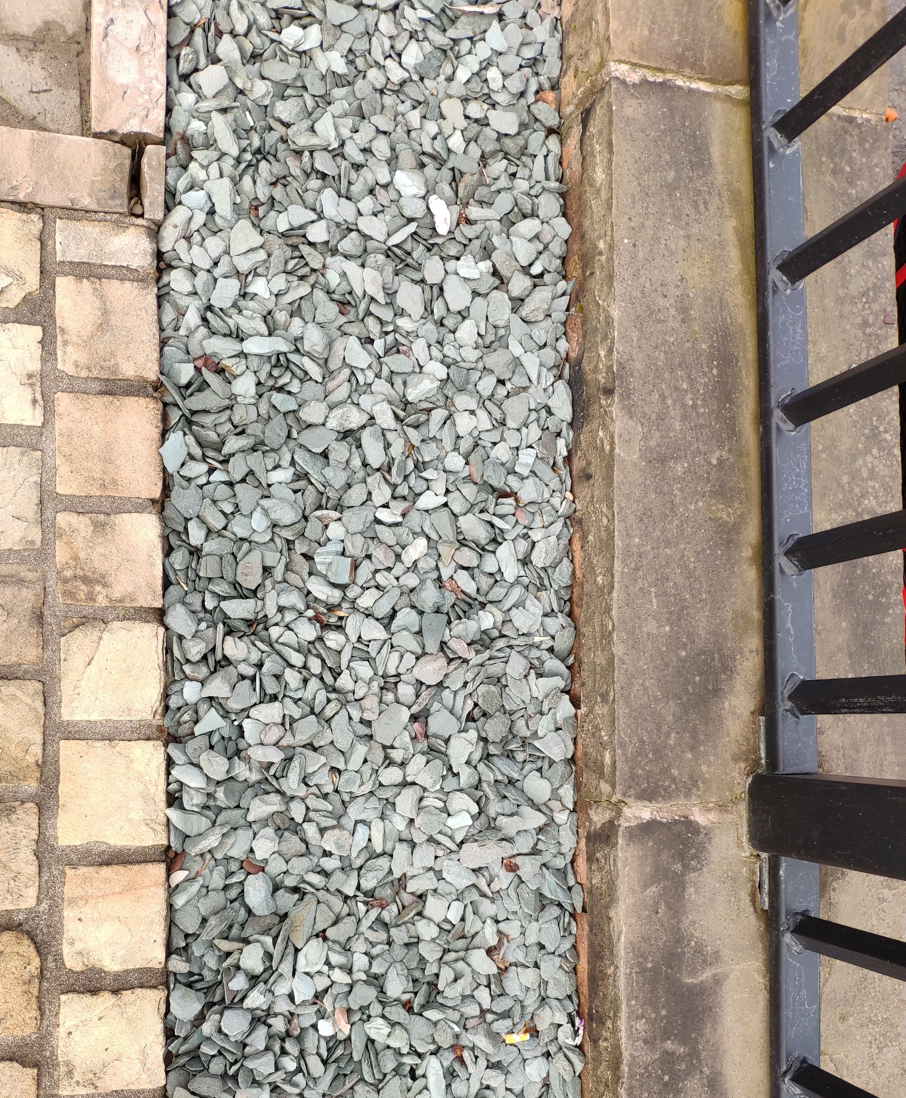 Green slate chippings laid in a strip between buff setts